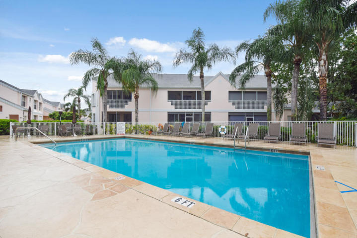 101 Muirfield Court, Unit F Jupiter, FL 33458 - Photo 19 of 20 a view of a swimming pool with a lawn chairs under an umbrella