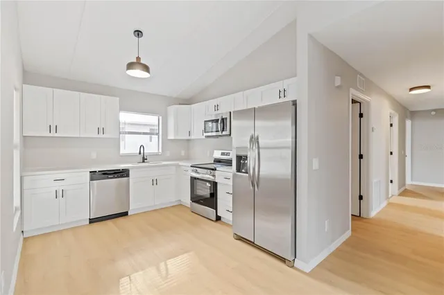a kitchen with stainless steel appliances white cabinets and a stove top oven