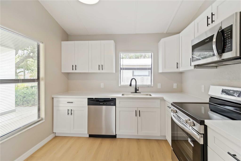 1368 21st Street Sarasota, FL 34234 - Photo 13 of 34 a kitchen with stainless steel appliances granite countertop a sink a stove a microwave and wooden cabinets