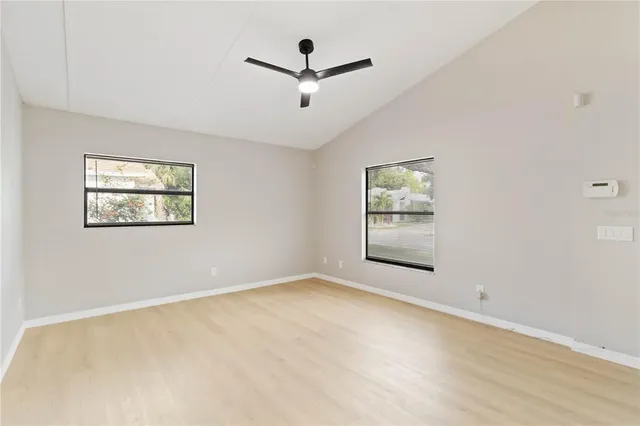 an empty room with windows and ceiling fan