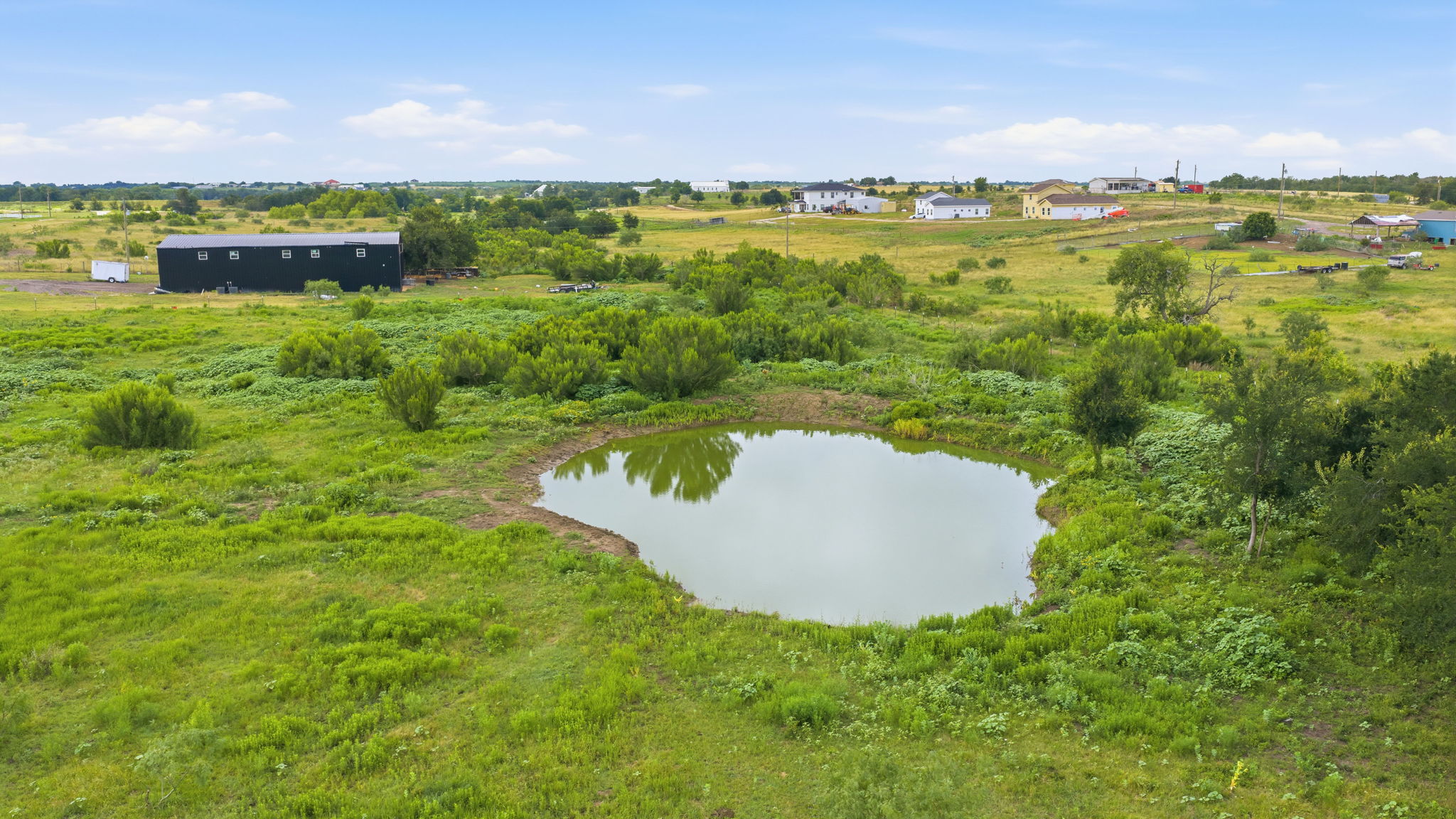 1701 County Road 466 Elgin, TX 78621 - Photo 22 of 24 A tranquil pond anchors this verdant landscape, offering a serene backdrop for future development.