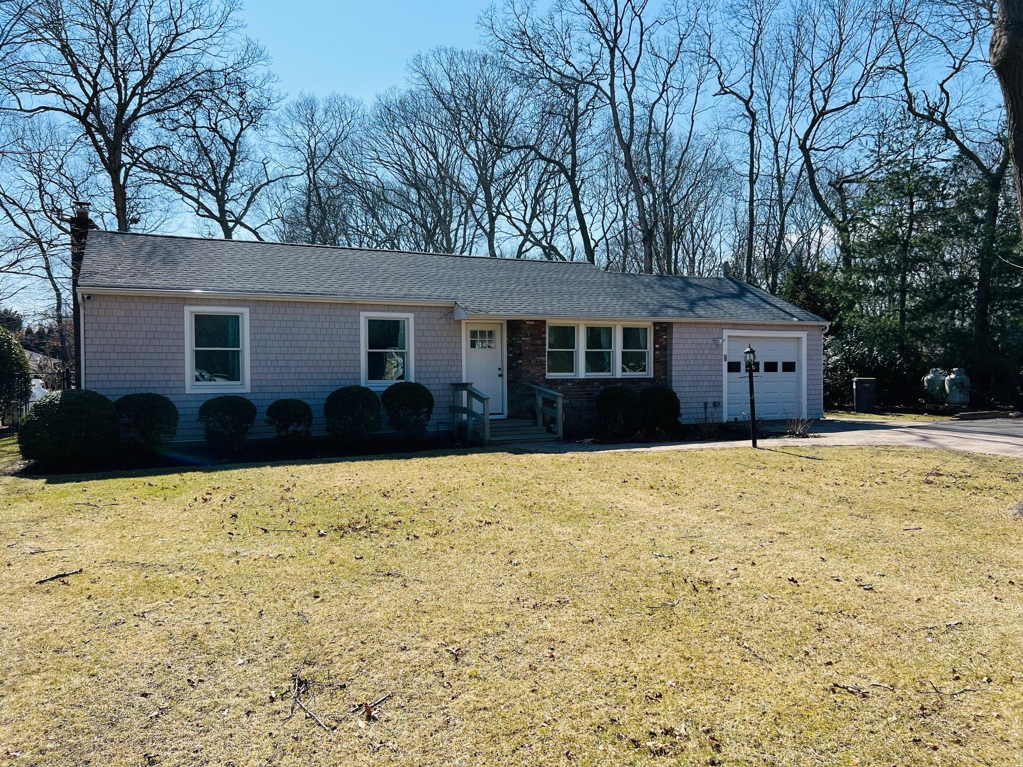Single story home with a garage, driveway, a chimney, and a front lawn