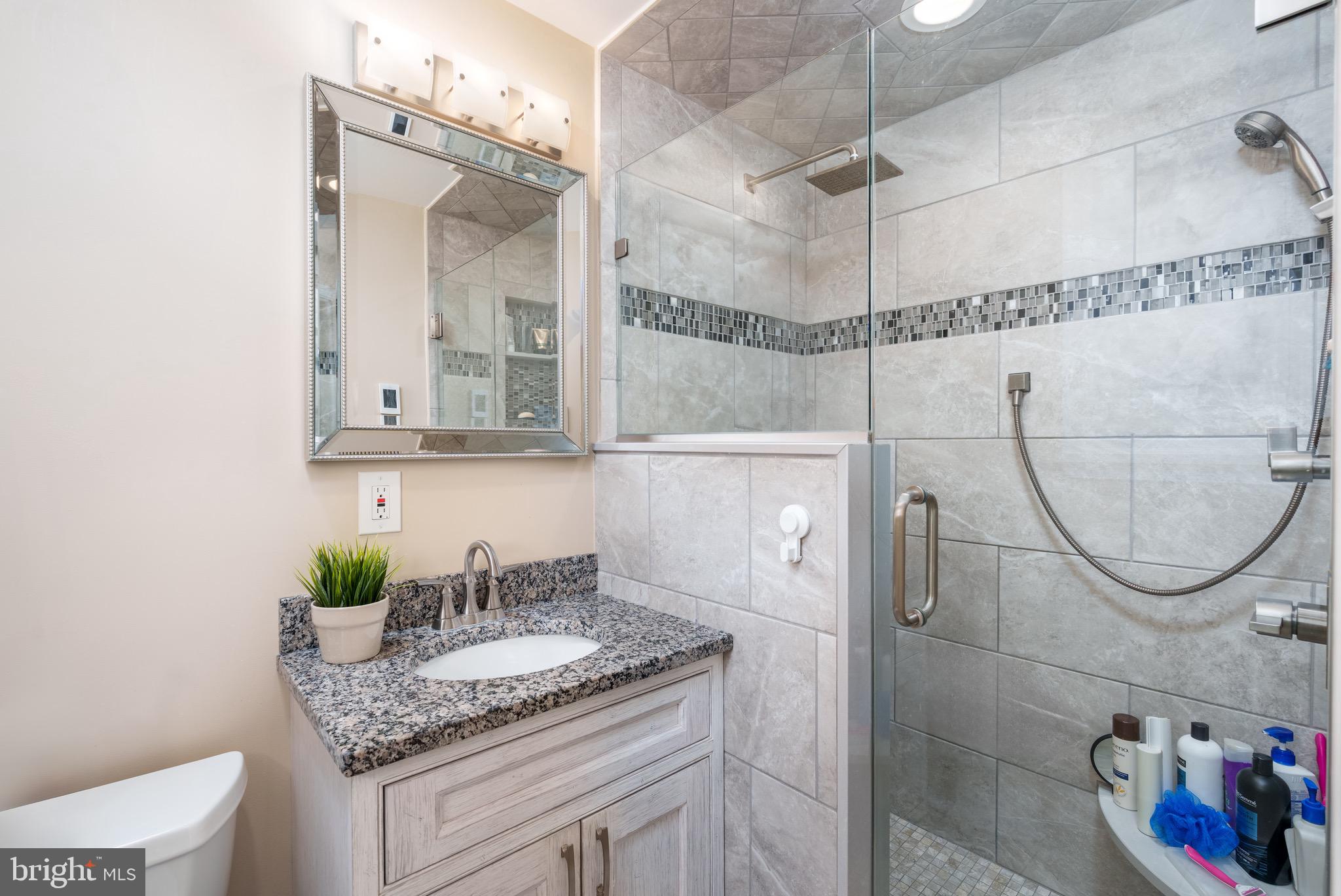1003 Piper Road Wilmington, DE 19803 - Photo 18 of 40 a bathroom with a granite countertop sink a mirror and shower