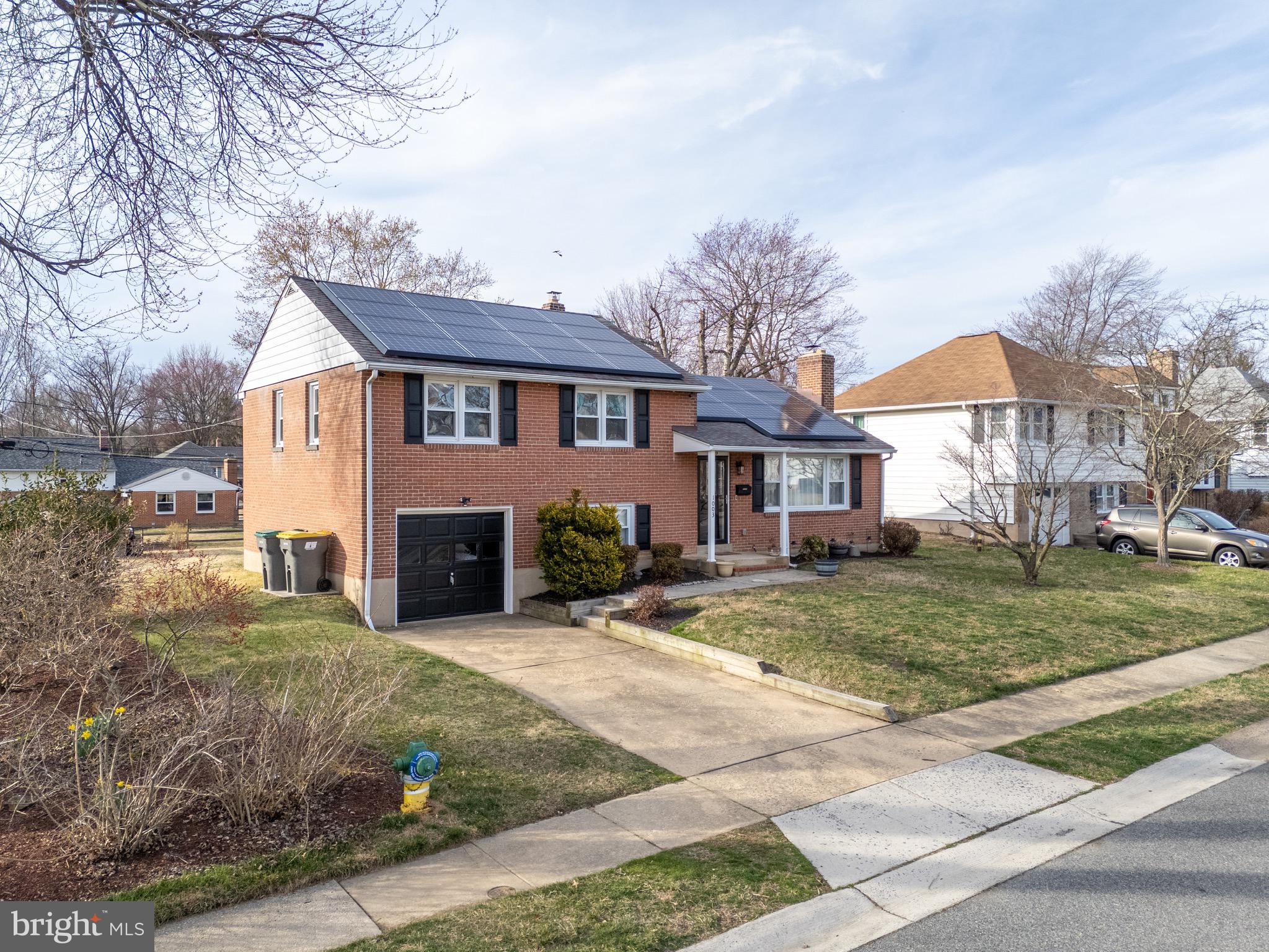 1003 Piper Road Wilmington, DE 19803 - Photo 3 of 40 a view of a yard in front of a brick house with large windows