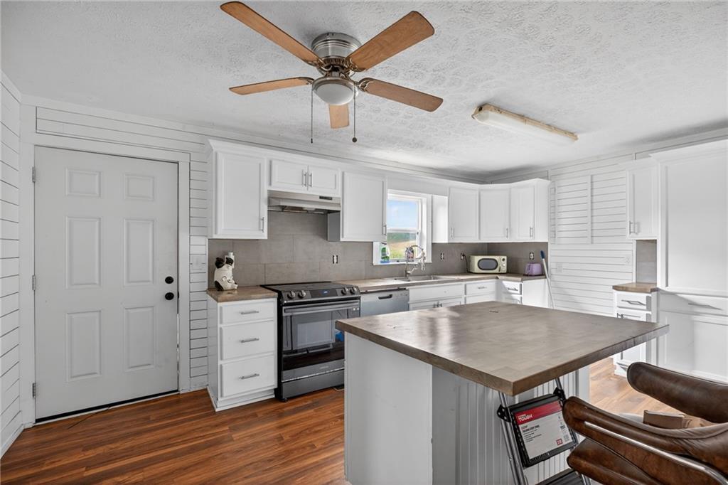 712 West 5th Highway Roopville, GA 30170 - Photo 8 of 29 a kitchen with stainless steel appliances a stove a sink dishwasher a refrigerator and white cabinets with wooden floor