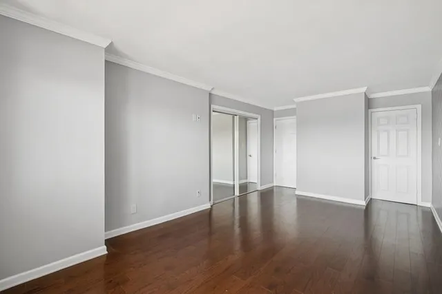 a view of an empty room with wooden floor and closet