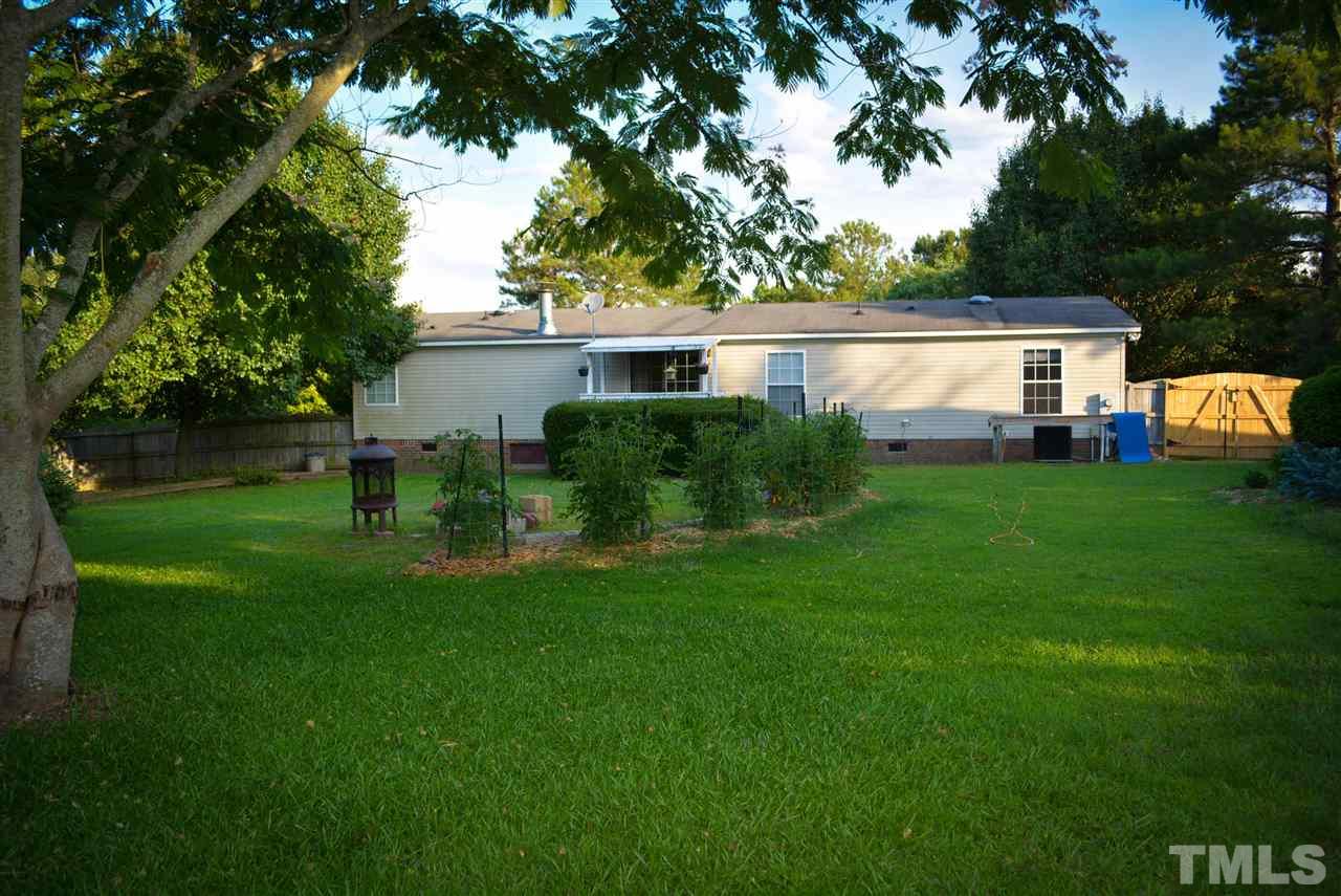 7236 Pecan Tree Street Willow Spring, NC 27592 - Photo 2 of 25 a view of a backyard with table and chairs potted plants and large tree
