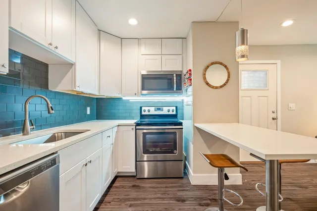 a kitchen with stainless steel appliances granite countertop a stove a sink and a microwave