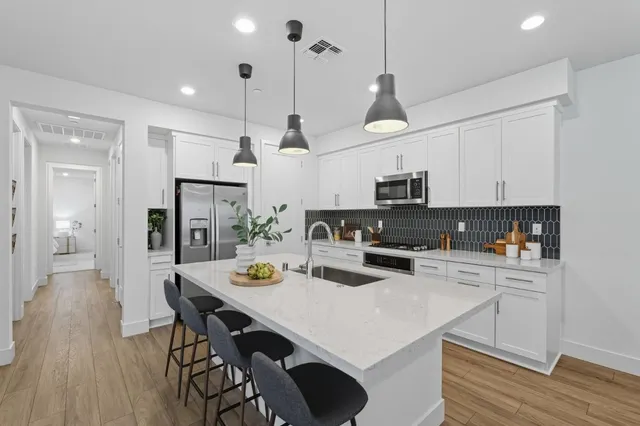 a kitchen with stainless steel appliances a stove a sink a dining table and chairs