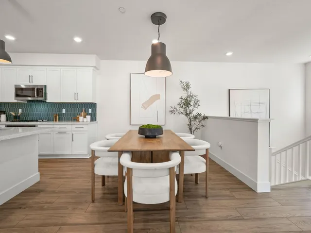 a kitchen with stainless steel appliances a dining table chairs and wooden floor