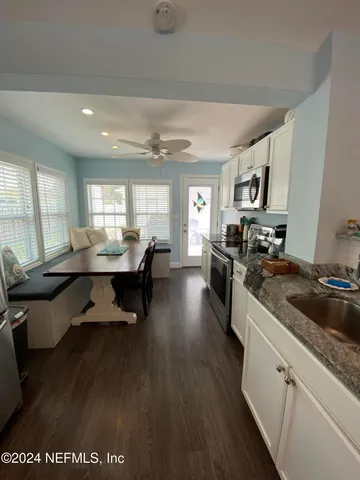 a kitchen with stainless steel appliances granite countertop a stove a sink dishwasher a refrigerator a dining table and chairs with wooden floor