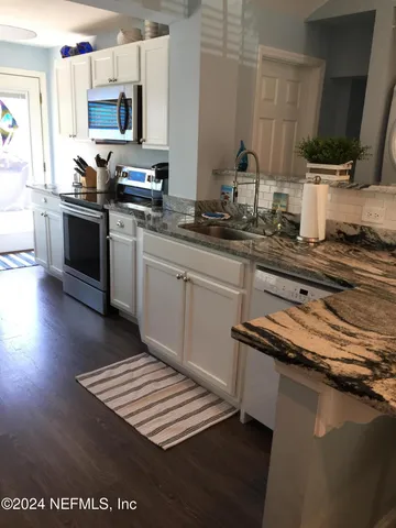 a kitchen with stainless steel appliances a sink a stove top oven a counter space and cabinets