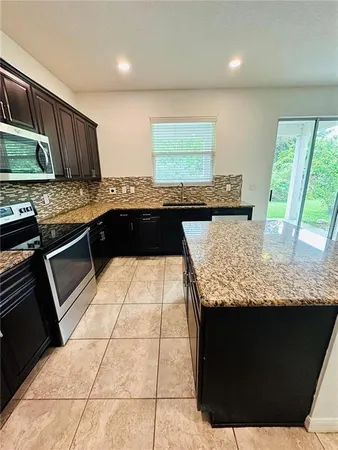 a kitchen with granite countertop a stove a sink and a microwave