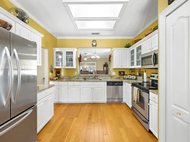 a kitchen with stainless steel appliances granite countertop a refrigerator a stove and white cabinets with wooden floor