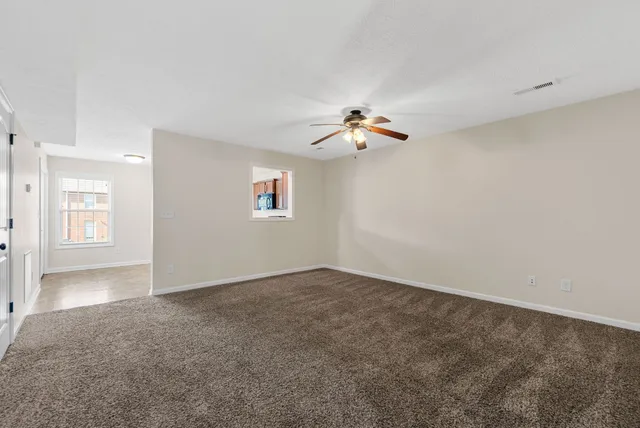 an empty room with windows and chandelier fan