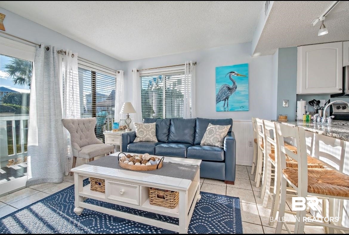 497 Plantation Road, Unit 1156 Gulf Shores, AL 36542 - Photo 6 of 28 Living room featuring a wainscoted wall, a textured ceiling, track lighting, and light tile patterned floors