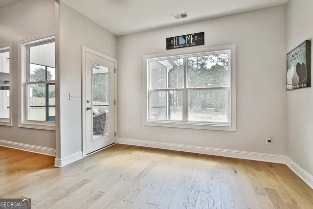 a view of an empty room with a window and wooden floor