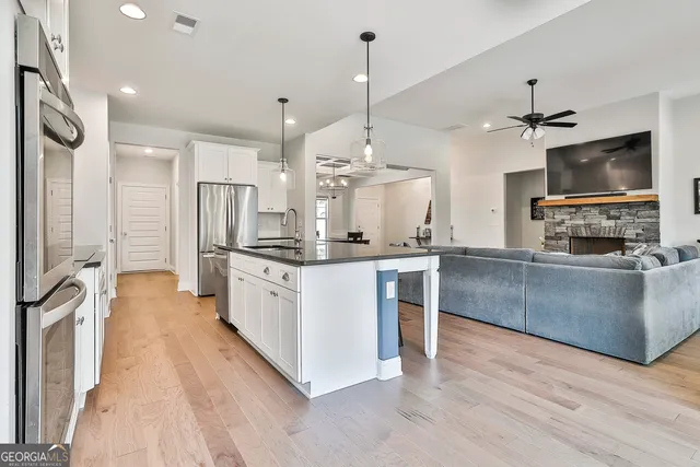 a large kitchen with granite countertop a large counter top space appliances and a ceiling fan