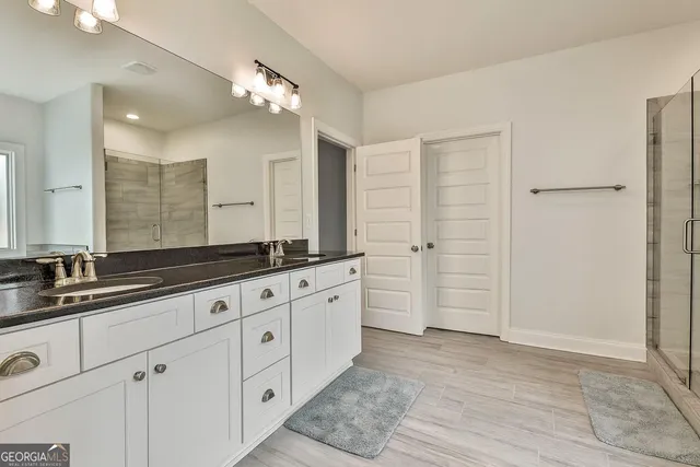 a spacious bathroom with a granite countertop double vanity sink a mirror and a bathtub