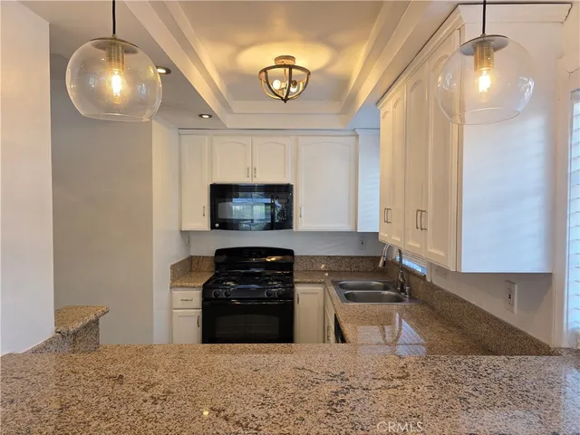a kitchen with stainless steel appliances granite countertop a stove a sink and a microwave