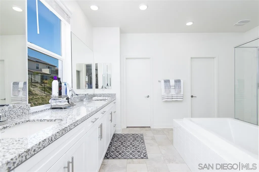 8828 Weston Road Santee, CA 92071 - Photo 23 of 25 a bathroom with a granite countertop sink a mirror and a bathtub