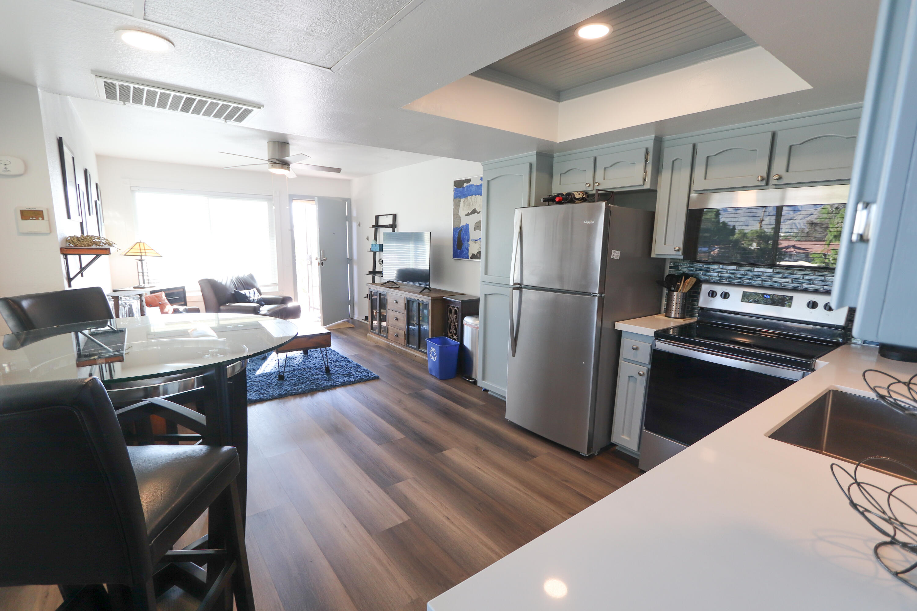 64291 Spyglass Avenue, Unit 2 Desert Hot Springs, CA 92240 - Photo 6 of 22 a kitchen with stainless steel appliances a refrigerator a stove a dining table and chairs with wooden floor