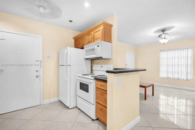 a kitchen with stainless steel appliances granite countertop a refrigerator a stove a sink and white cabinets