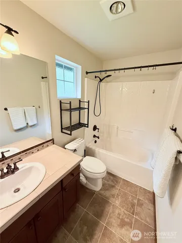 a bathroom with a sink a toilet a mirror a vanity and shower