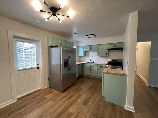 a kitchen with stainless steel appliances a refrigerator a sink dishwasher a stove and white countertops with wooden floor