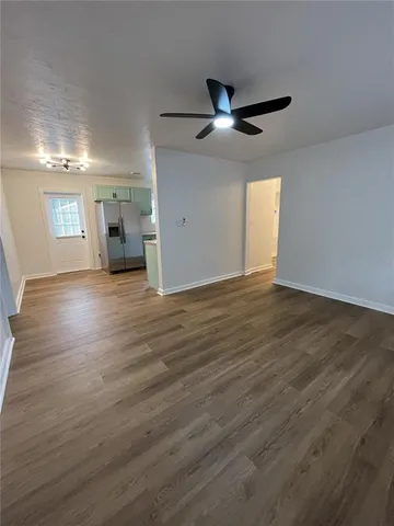 an empty room with wooden floor cabinet and windows
