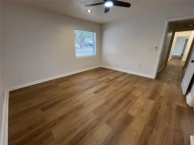 a view of an empty room with wooden floor and a window