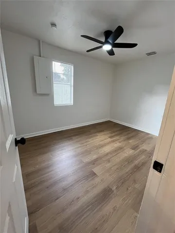 an empty room with wooden floor a ceiling fan and windows