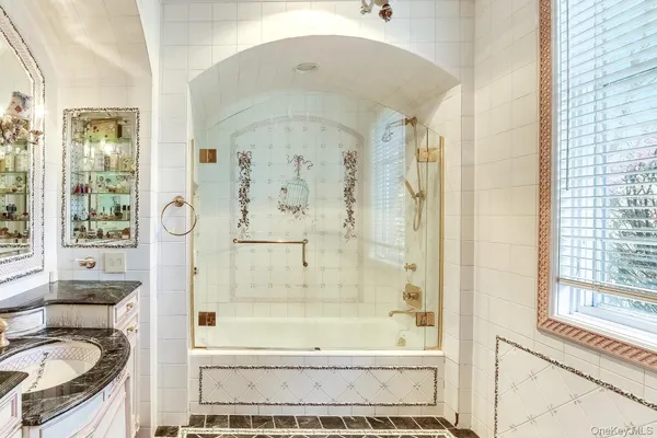 a bathroom with a granite countertop tub shower and mirror