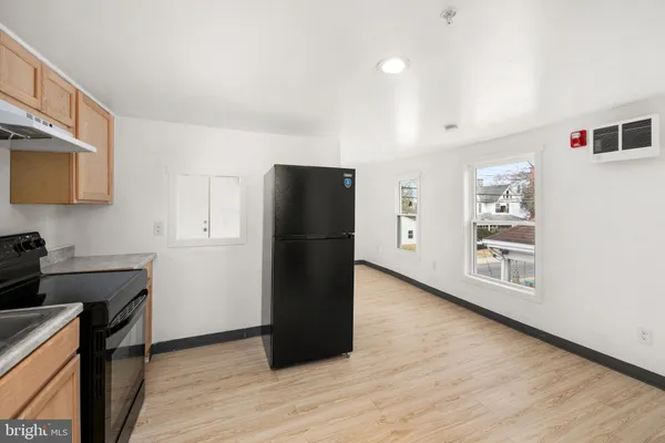 a view of a kitchen with refrigerator and wooden floor
