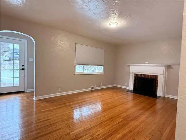 an empty room with wooden floor fireplace and windows