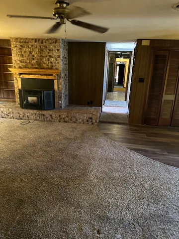 a view of an empty room with wooden floor fireplace and a window