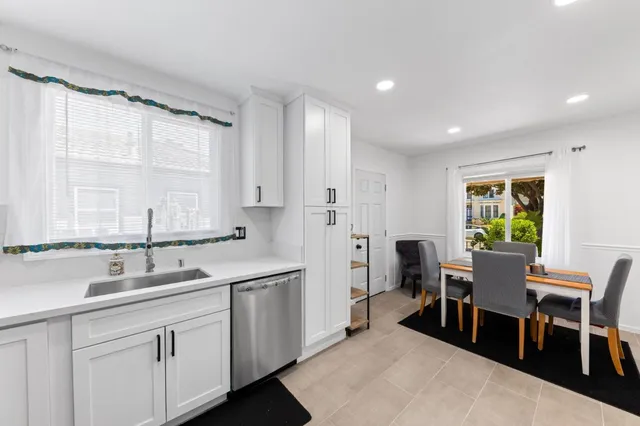 a large kitchen with kitchen island white cabinets and stainless steel appliances