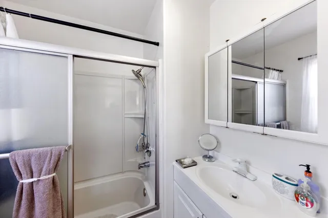 a bathroom with a tub shower sink and mirror