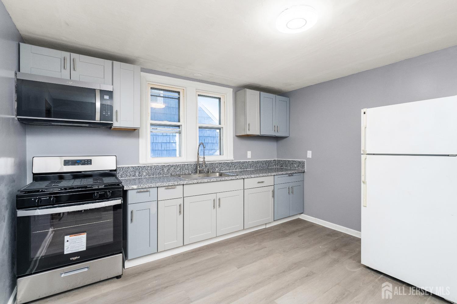 225 Kuser Road Hamilton, NJ 08619 - Photo 7 of 26 a kitchen with granite countertop a sink stainless steel appliances and white cabinets