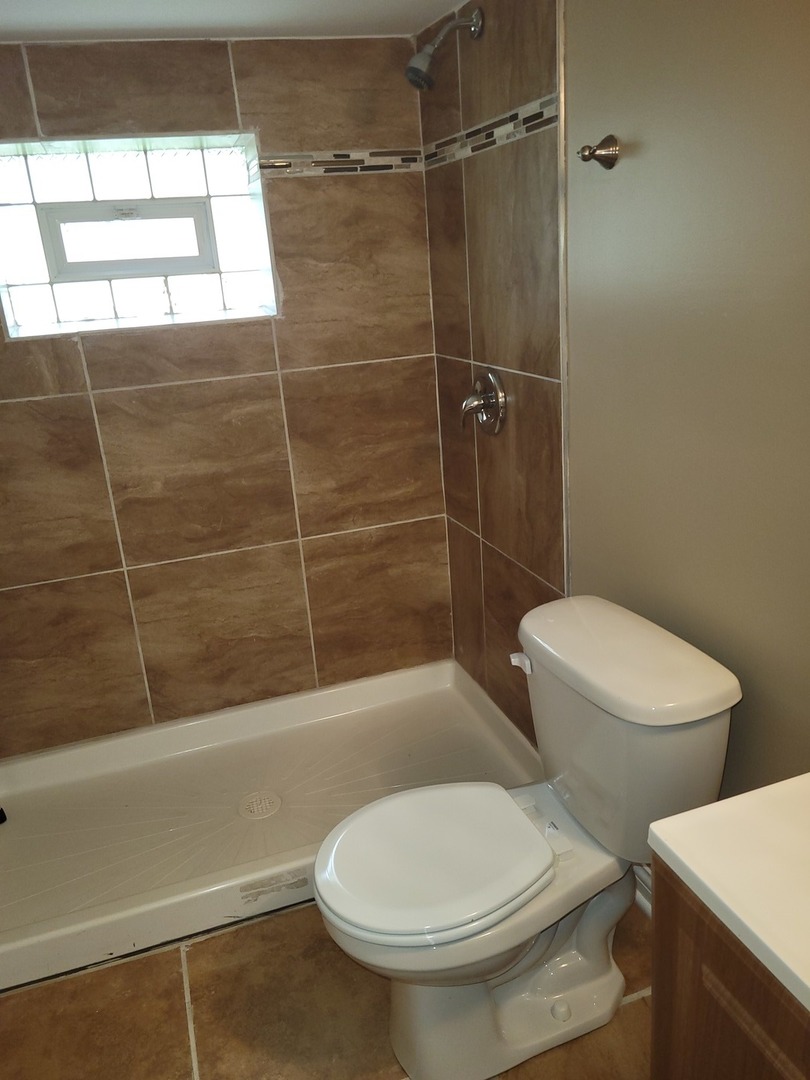 8529 South Rhodes Avenue Chicago, IL 60619 - Photo 12 of 16 a white toilet sitting next to a bath tub and shower