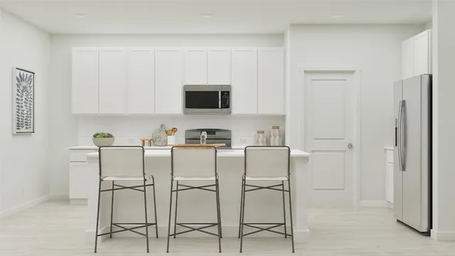 a white kitchen with stainless steel appliances white cabinets and a stove top oven