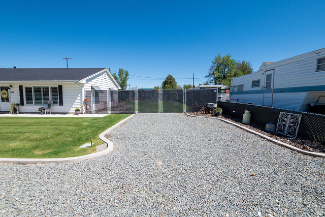 340 West 100 N Street Beaver, UT 84713 - Photo 5 of 37 Gravel driveway with concrete curbing and black chain-link fencing