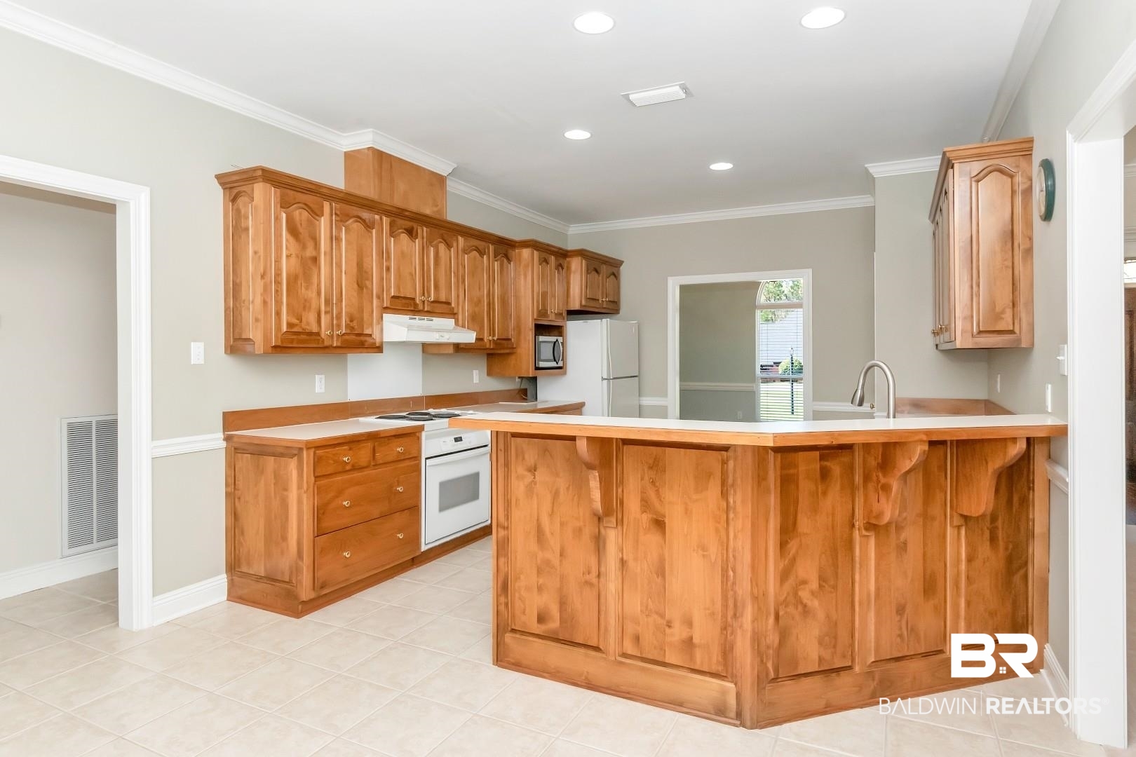 6090 Celeste Road Saraland, AL 36571 - Photo 7 of 38 Kitchen with light countertops, a peninsula, under cabinet range hood, white appliances, and visible vents