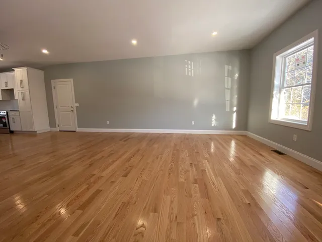 a view of an empty room with wooden floor and stairs