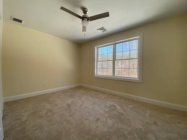 an empty room with fan hallway and closet area