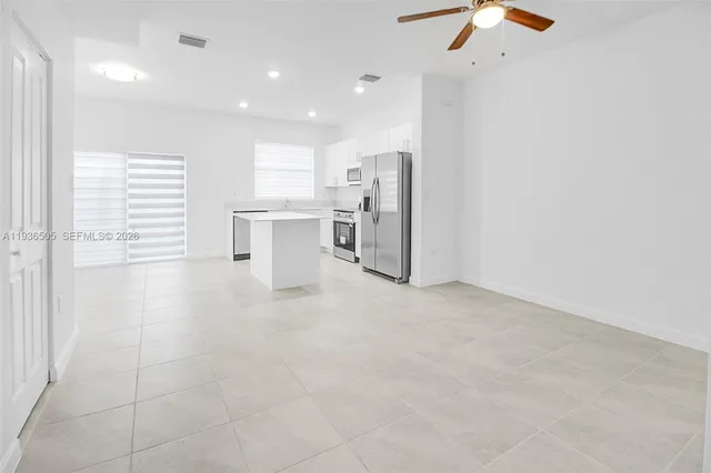 a view of a kitchen with a sink and dishwasher a refrigerator with white cabinets