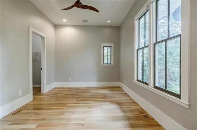 an empty room with wooden floor and windows