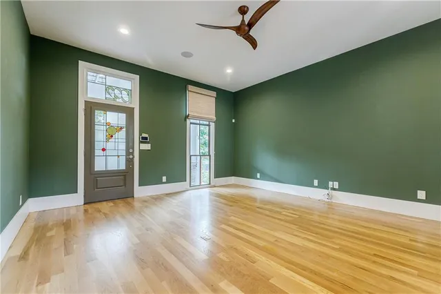 a view of empty room with wooden floor and fan