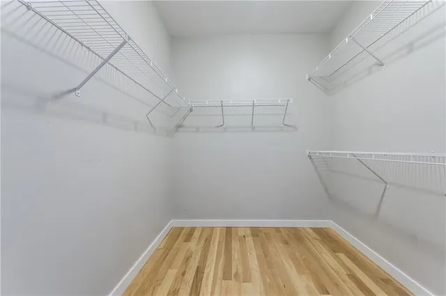 a view of an empty room with wooden floor and a ceiling fan