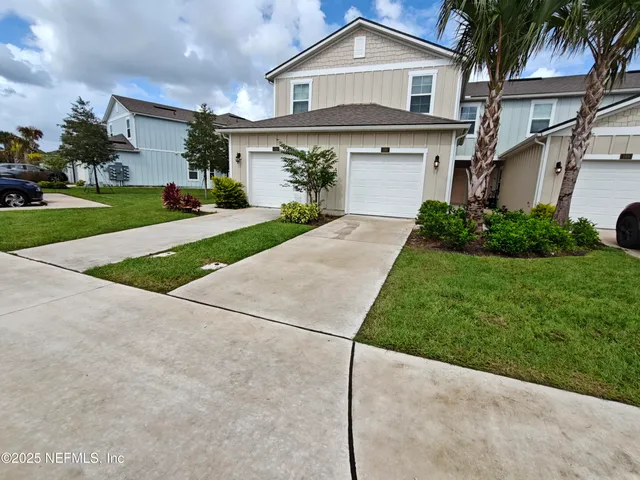 a front view of a house with a garden and palm trees